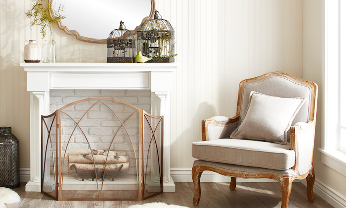 fausse cheminée décorative à cadre blanc et fond en briques banches et buches en déco, fauteuil en bois vintage, cages à oiseaux rétro