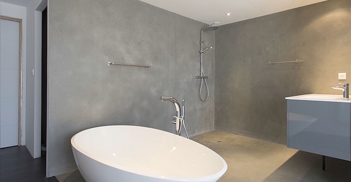revêtement béton ciré sur sol et murs de salle de bain avec baignoire ilot ovale sans carrelage