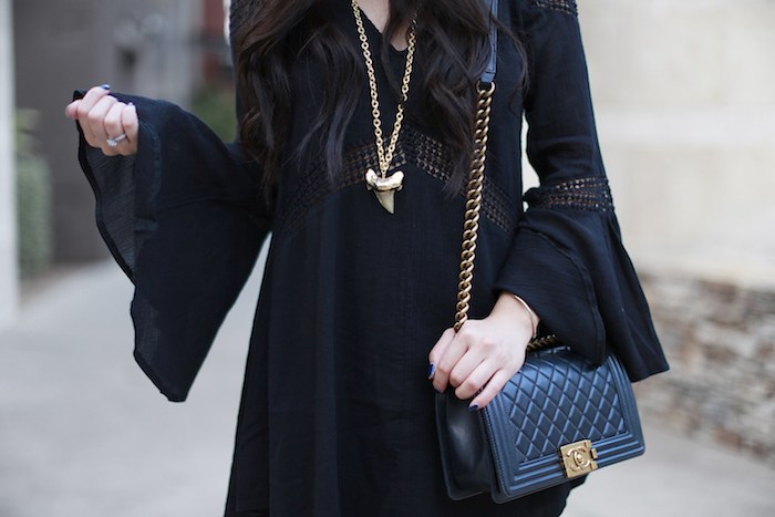 idée de look déguisement sorcière femme, robe noire avec des manches longues évasées, sac à main noir, collier or sorcière