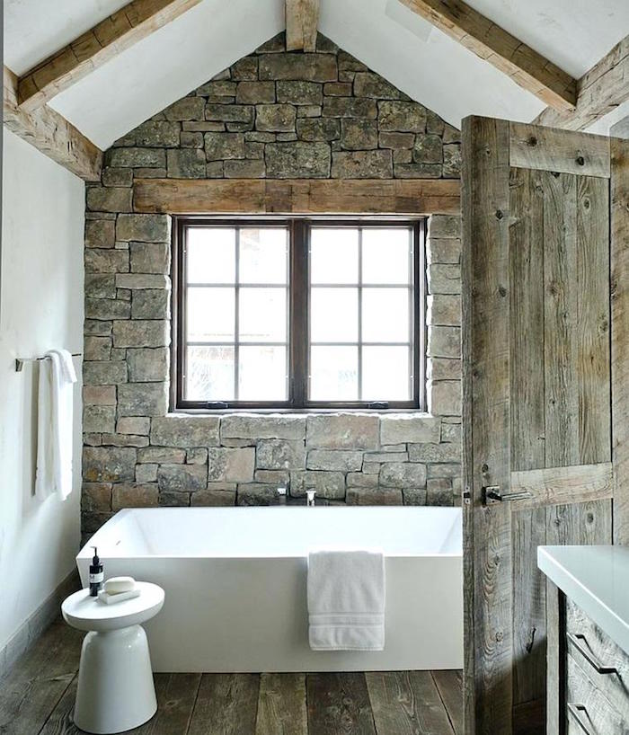 salle de bain ancienne rénovée avec pierres grises anciennes, sol en parquet et porte en bois vintage