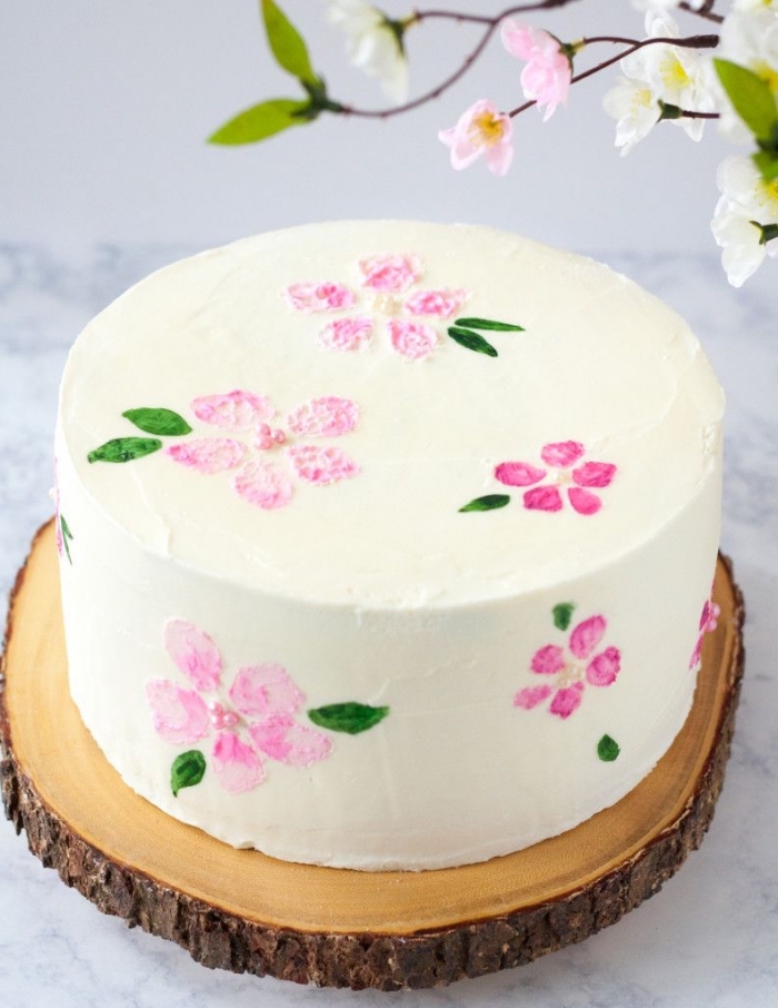 technique facile pour réaliser un dessin gateau anniversaire floral sur un glaçage de crème au beurre, déposé sur un rondin de bois