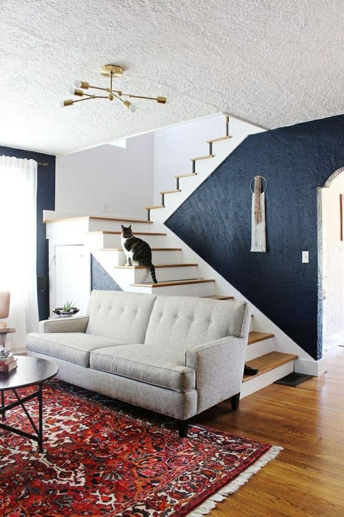 salon espace ouvert près d'un escalier en blanc et bois, sol en bois, sofa gris clair, plafonnier métal doré