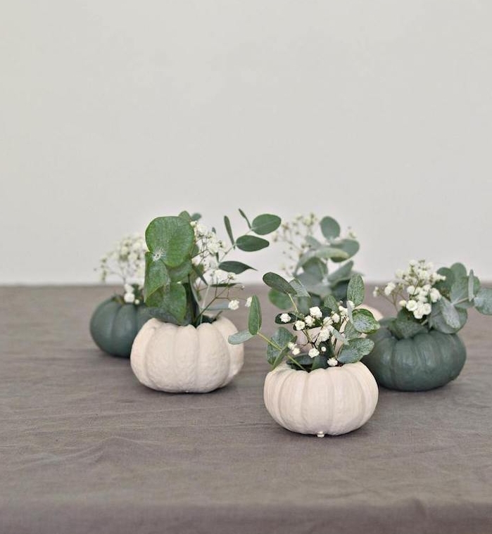 vase de fleur halloween en citrouille creusée avec de petits bouquets de fleurs blanches et feuilles vertes, activités manuelles halloween