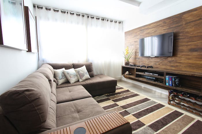 tv en face d'un canapé d angle gris sur tapis gris, marron et beige, comment accrocher un tv au mur habillé de bois
