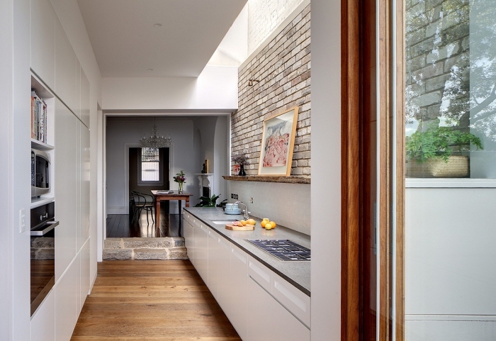 modèle petite cuisine aménagée en parallèle, déco de cuisine blanc et bois avec mur en briques et plancher bois