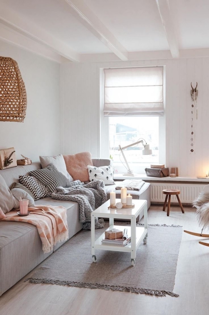 petit salon hygge deco douce et chaleureuse, avec un grand canapé gris recouvert de coussins décoratifs 