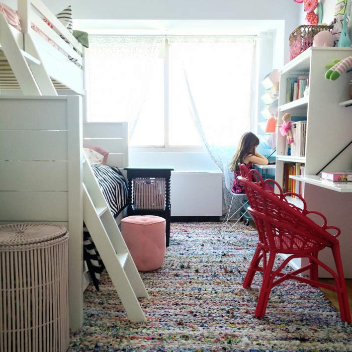 tapis multicolore, lit mezzanine en bois blanc avec échelle, chaises rouges tressées, bibliothèque blanche, panier beige, tabouret rose