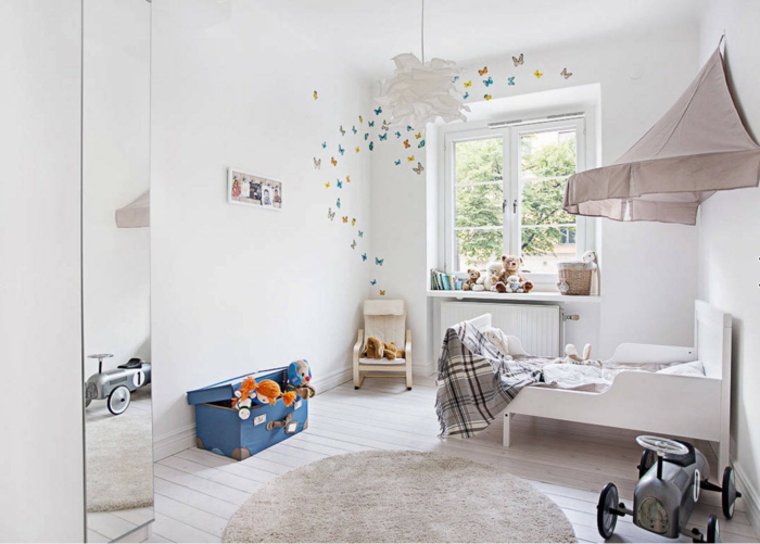 aménagement de petite chambre enfant, tapis gris clair, lit et tête de lit originale, plafonnier blanc, grand miroir, coffre à jouets valise vintage