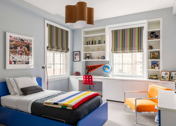 grand lit au cadre bleu, fauteuil orange, bureau avec rangement blanc, photo de sport, rideaux bateaux