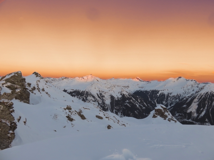 incroyable photo du coucher du soleil dans les montagnes, paysage de neige avec ciel orange et sommets enneigés