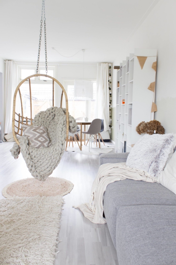 un tapis cocooning posé en dessous d'un fauteuil à suspendre cosy pour un petit coin de détente dans le salon scandinave