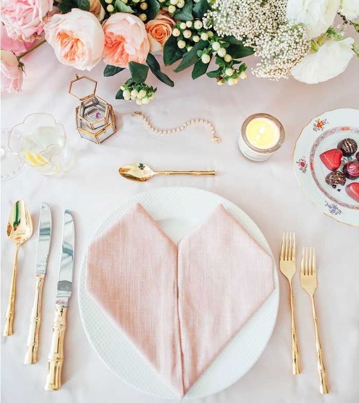décoration de table mariage romantique, pliage serviette coeur avec deux serviettes en tissu rose, couverts dorés, composition florale mariage, bougeoirs romantiques