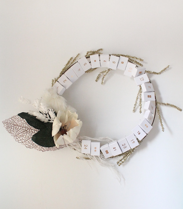 couronne de noel originale avec des boîtes d allumettes blanches et chiffres notés dessus et décoration de fleurs et branches artificielles