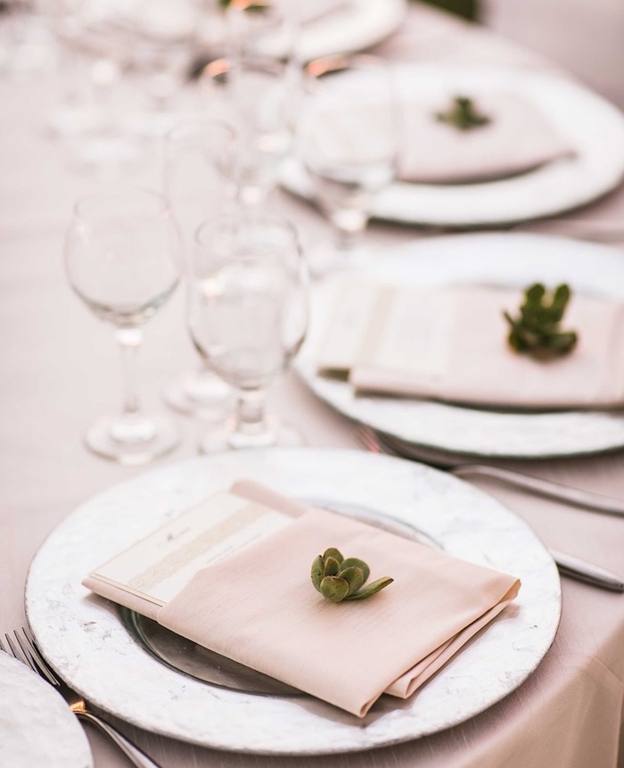 pliage pochette de serviette en tissu porte menu décorée de petite succulente, nappe beige et verres à vin