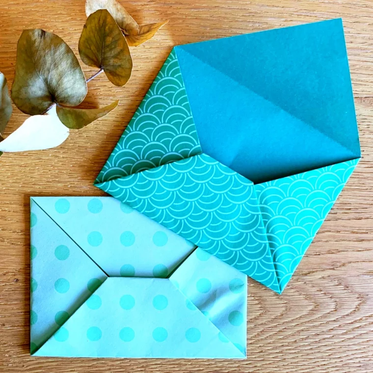 deux enveloppes en origami vertes avec motifs sur table en bois