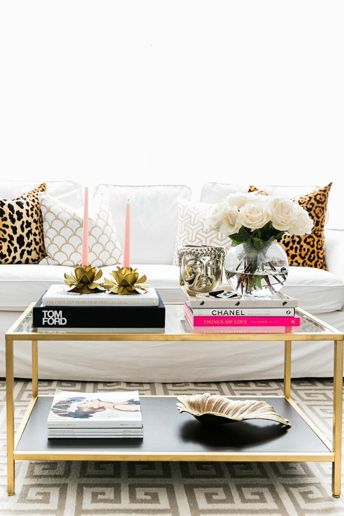 table de salon encadrement doré, livres en rose, blanc et noir, coquille, coussins déco, tapis motifs géométriques