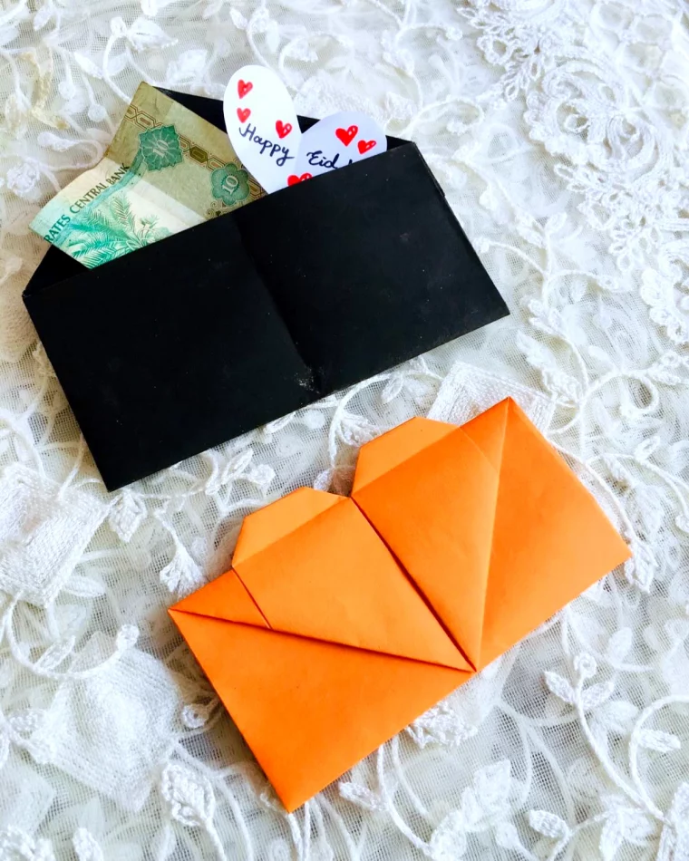 enveloppe noire en origami avec billet et coeurs en papier d'une enveloppe orange en forme de coeur