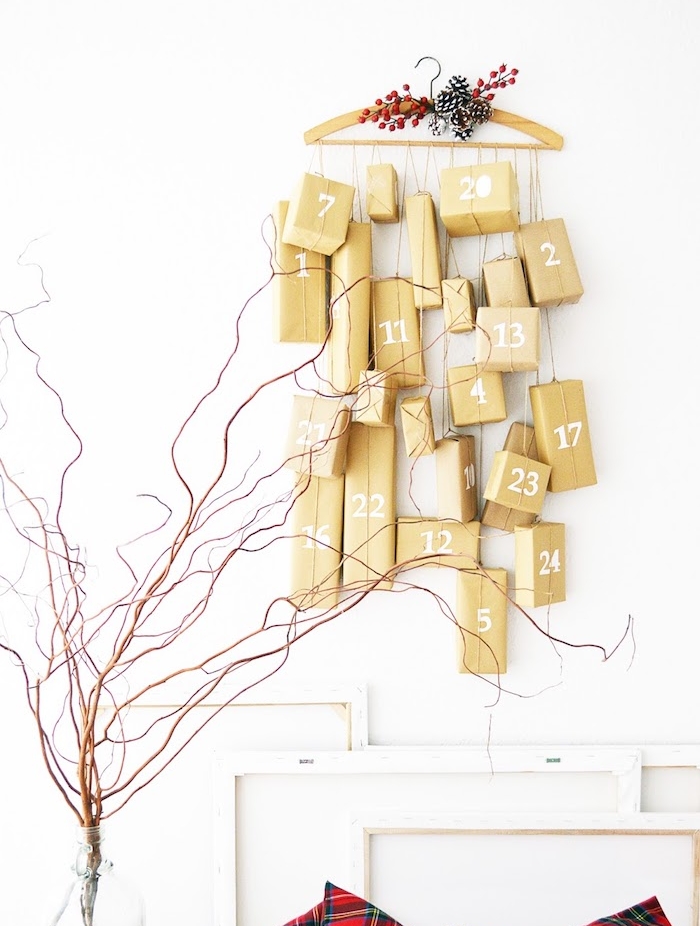 exemple de calendrier de l avent original en petits cadeaux emballés suspendus sur un cintre en vois décoré pommes de pin et houx