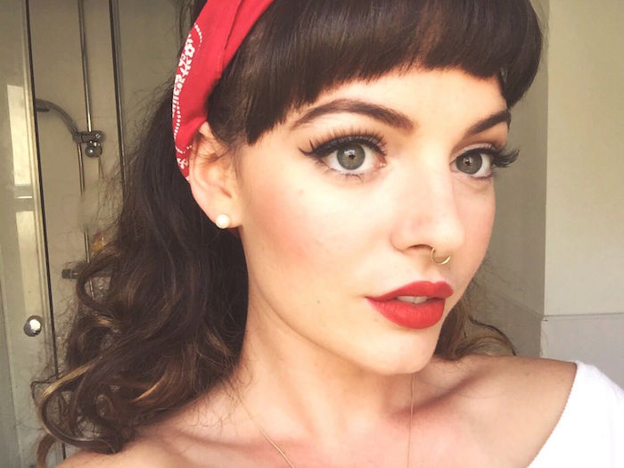 exemple de maquillage dans le style pin up avec coiffure des années 50 avec frange et bandana rouge dans les cheveux