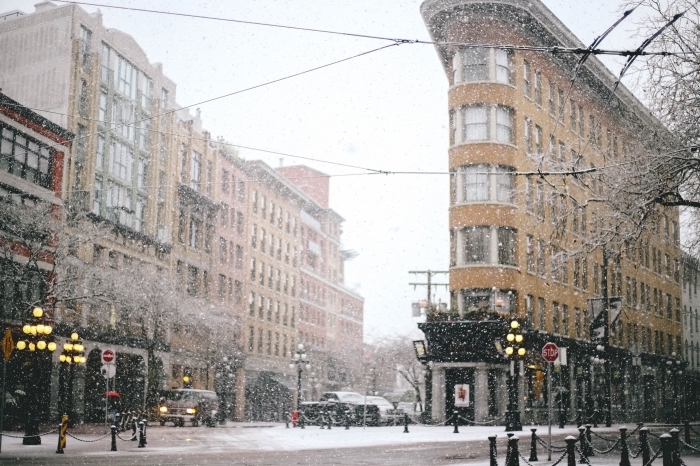 image de noel gratuite a telecharger, photo de la neige qui tombe dans une ville en hiver aux lumières allumées