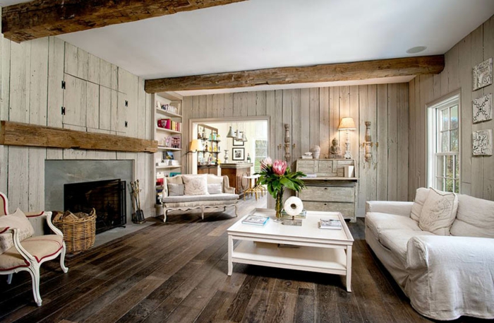 sol en bois, table de salon blanche, chaise ancienne avec coussin de lin, cheminée et lambris mural bois