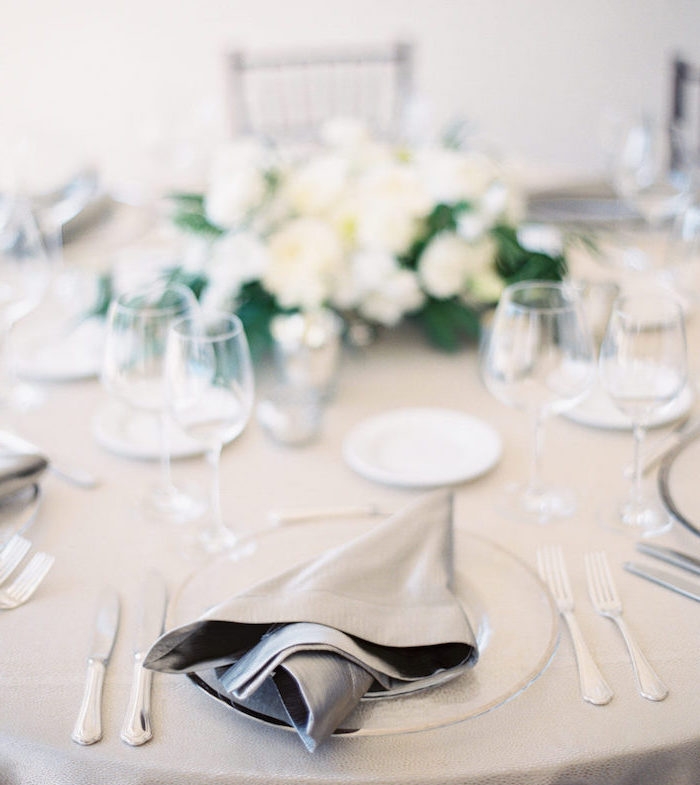 pliage de serviette facile et nonchalant avec serviette grise dans assiette blanche, couverts de table élégants, pièce centrale décorative en fleurs blanches