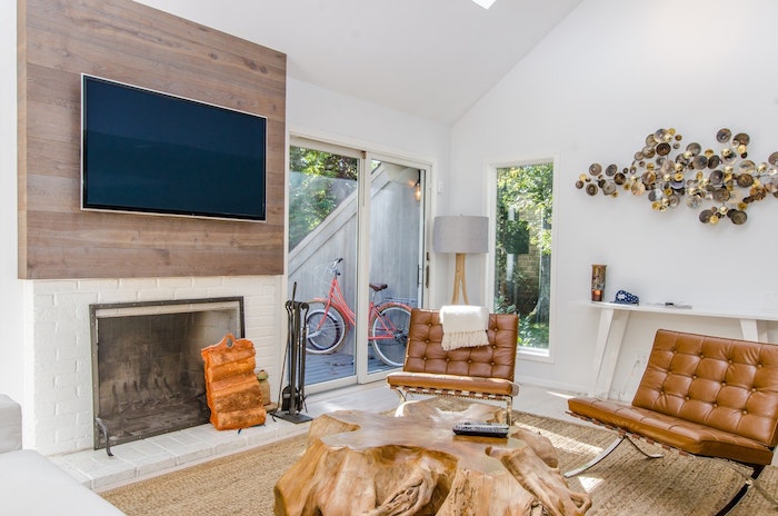 choisir sa télévision écran plat au dessus d'une cheminée, tapis beige, chaises en cuir, table en tronc d arbre, tv en hauteur