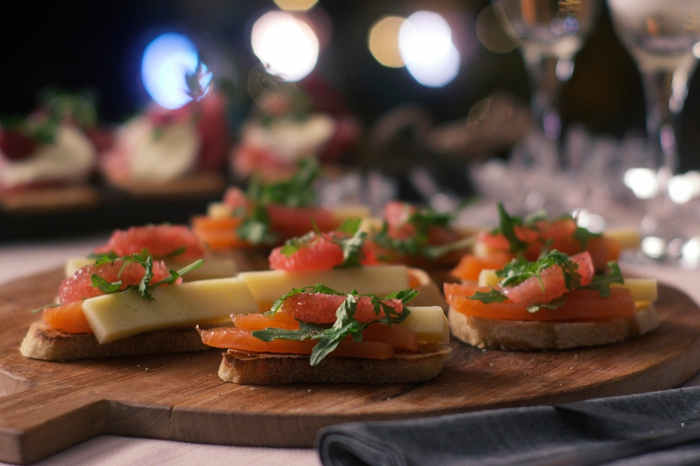 plat de service en bois, tartines au saumon et au fromage, amuse bouche apéritif facile sur la table de fête