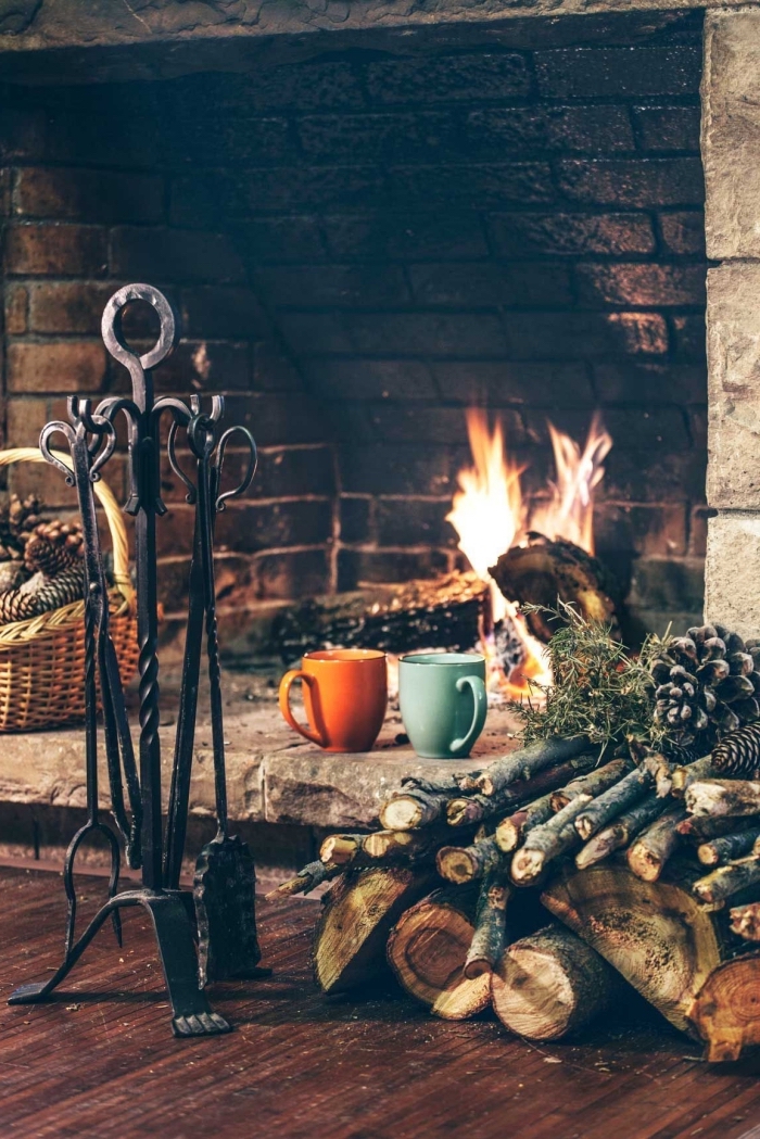 image cocooning d'un coin cheminée traditionnel avec un panier déco en rotin plein de pommes de pin 