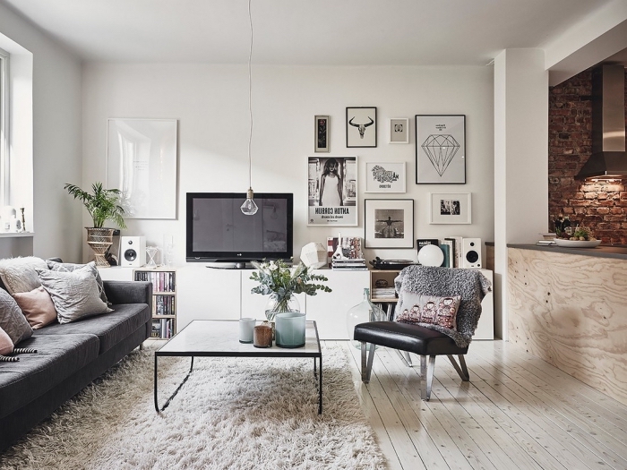 ambiance déco scandinave de style hygge avec un tapis cocooning, un canapé confortable et un parquet de bois blanchi qui illumine l'intérieur