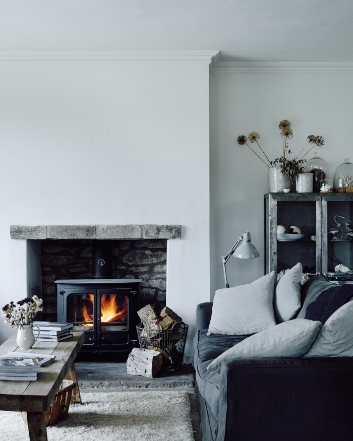 deco salon gris de style rustique chic aux accents industriels avec un insert dans une cheminée à foyer ouvert, une table en bois rustique et un canapé gris moelleux