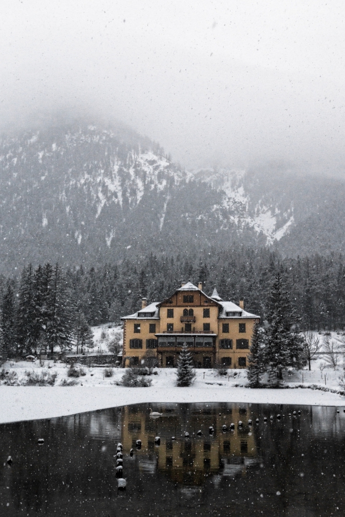 idée image neige qui tombe pour fond d'écran pc, photo de paysage montagnes enneigées et maison au bord de lac