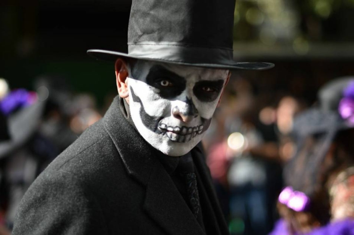 maquillage terrifiant pour halloween, chapeau noir cylindre, dents monstrueuses, cavités oculaires noires, tenue noire