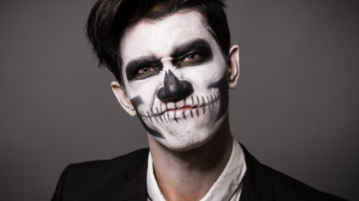 maquillage halloween monochrome, tête de mort créé sur le visage d'un homme avec peintures visage
