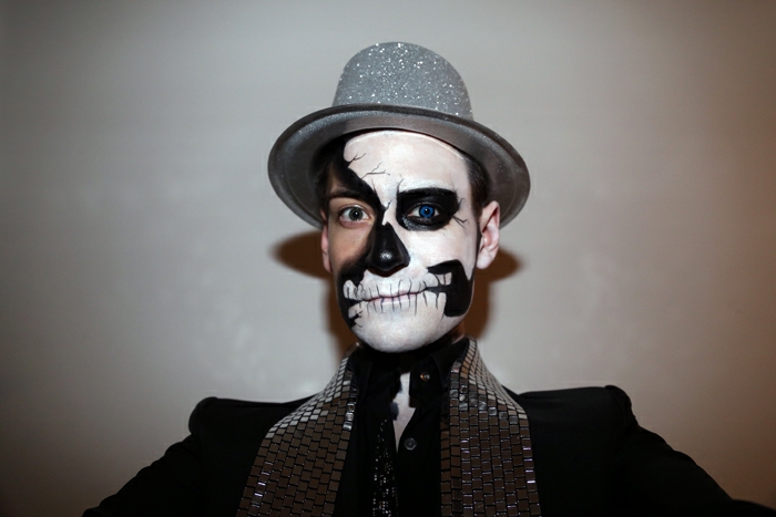 maquillage tête de mort, chapeau gris scintillant, costume noir, maquillage demi tête de mort en noir et blanc