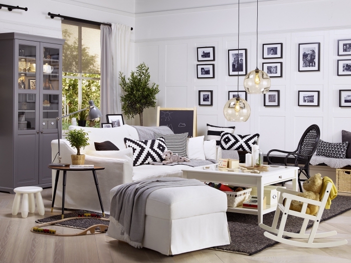 deco salon gris et blanc qui mélange les styles industriel, scandinave et vintage, avec un grand canapé blanc cosy, des accents en bois naturel et un mur de cadres noir et blanc