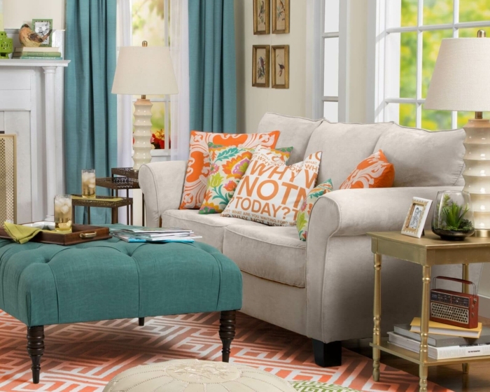 tapis aux motifs géométriques, ottomane bleue, coussins avec scripts, sofa gris, table basse de deux niveaux, rideaux bleus