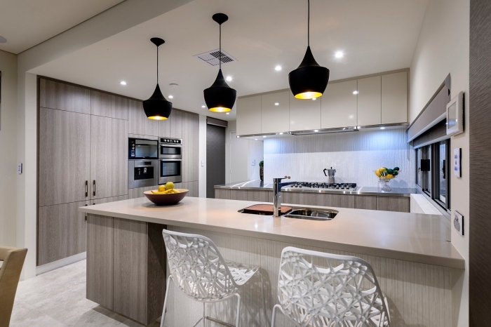 design intérieur tendance moderne dans une cuisine blanc et bois, exemple agencement cuisine avec îlot et lampes suspendues