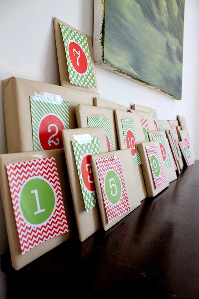 des simples paquets cadeau en papier kraft rangés sur un meuble bois avec une peinture accrochée au mur, calendrier de l avent adulte et enfant