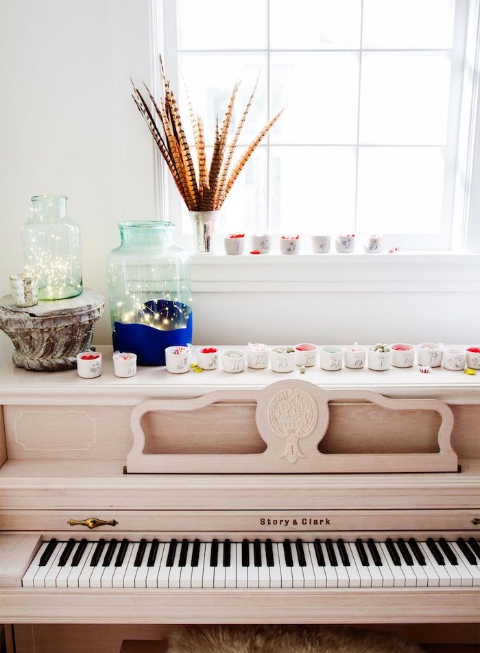 calendrier de l avent maison, petites coupelles remplies de gourmandises sur une piano, bocal avec guirlandes lumineuses décoratif