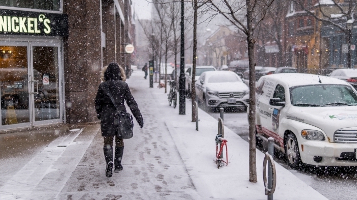 idée pour fond d'écran original pc, paysage d'hiver au centre ville, photo de flocons de neige qui tombent et femme qui marche dans une ville enneigée
