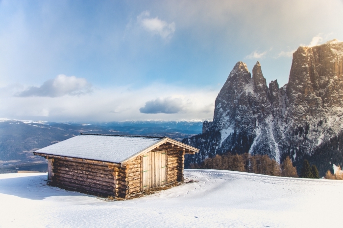 joli paysage de noel ou d'hiver, photo de cabane de bois sur un colin dans les montagnes enneigées, image lever du soleil en hiver