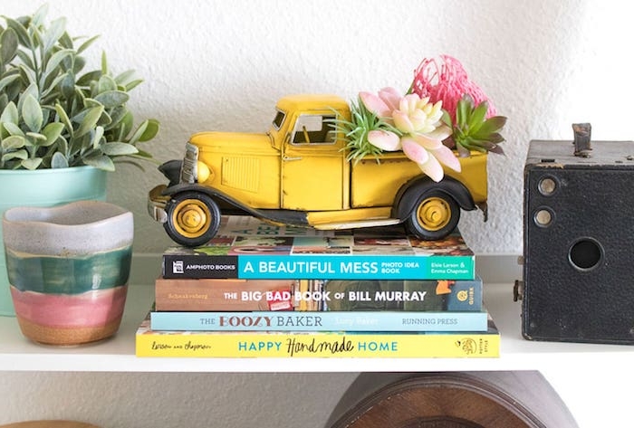 succulents plantés dans un joeut voiture jaune et autre plante verte à côté,, pile de livres, plantes grasses d intérieur