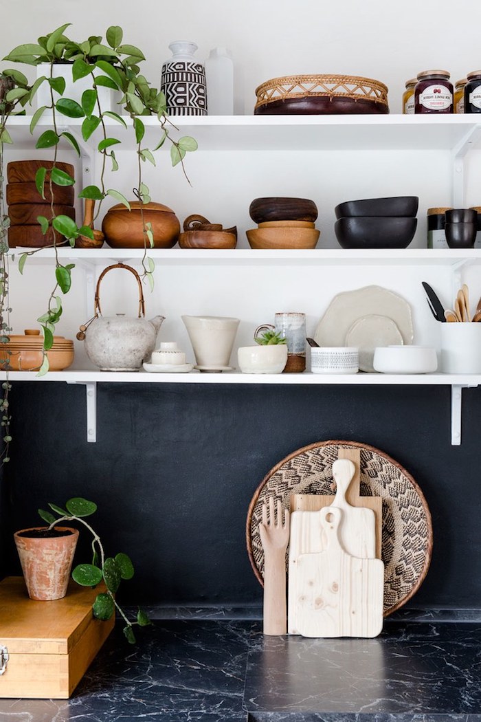 étagères ouvertes blanches avec des ustensiles de cuisine exposés, crédence noire et plan de travail cuisine marbre noir, deco africaine avec plante tombante intérieur