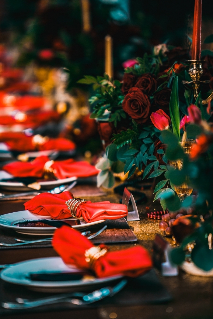 magnifique décoration de table de Noel avec bouquets de roses rouges et bougeoirs dorés, idée pliage serviette etoile ou papillon
