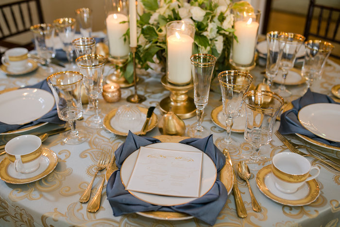 décoration élégante de mariage avec serviettes en tissu pliées en forme de fleur de lotus sous assiette, couverts, vaisselle et bougeoirs dorés