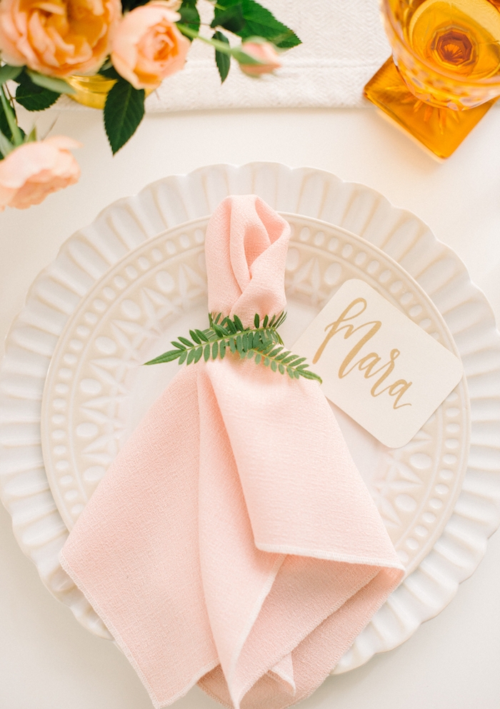décoration élégante de table mariage avec serviette pliage traditionnel avec anneau floral, marque place étiquette, assiettes blanches, bouquet de roses au centre