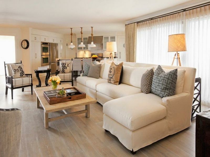 sofa d'angle crème, table basse bois, sol en bois, cuisine et salon style campagne, trois lampes suspendues blanches