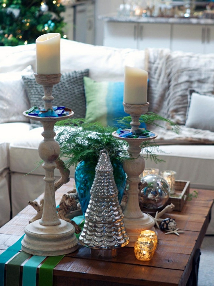 deux grandes bougies et bougeoirs hauts, decoration de table de noel, sapin couleur métalisée, bois flotté, pommes de pin, sofa, sapin de noel