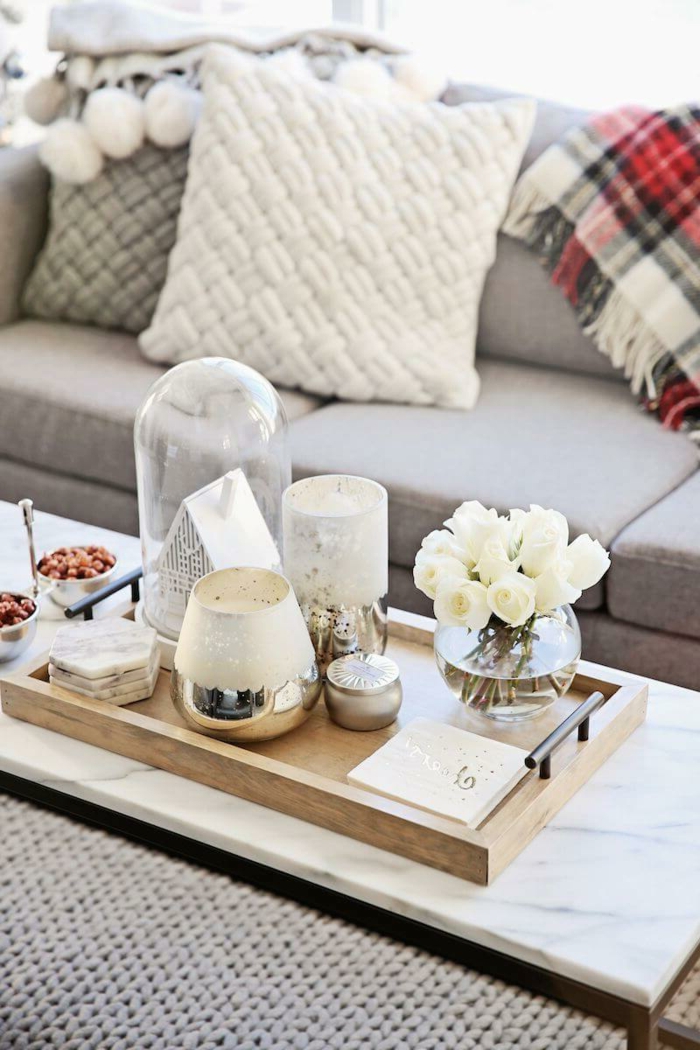 canapé gris clair, plateau en bois, vases en verre et métal argenté, coussins décoratifs, plaid carré